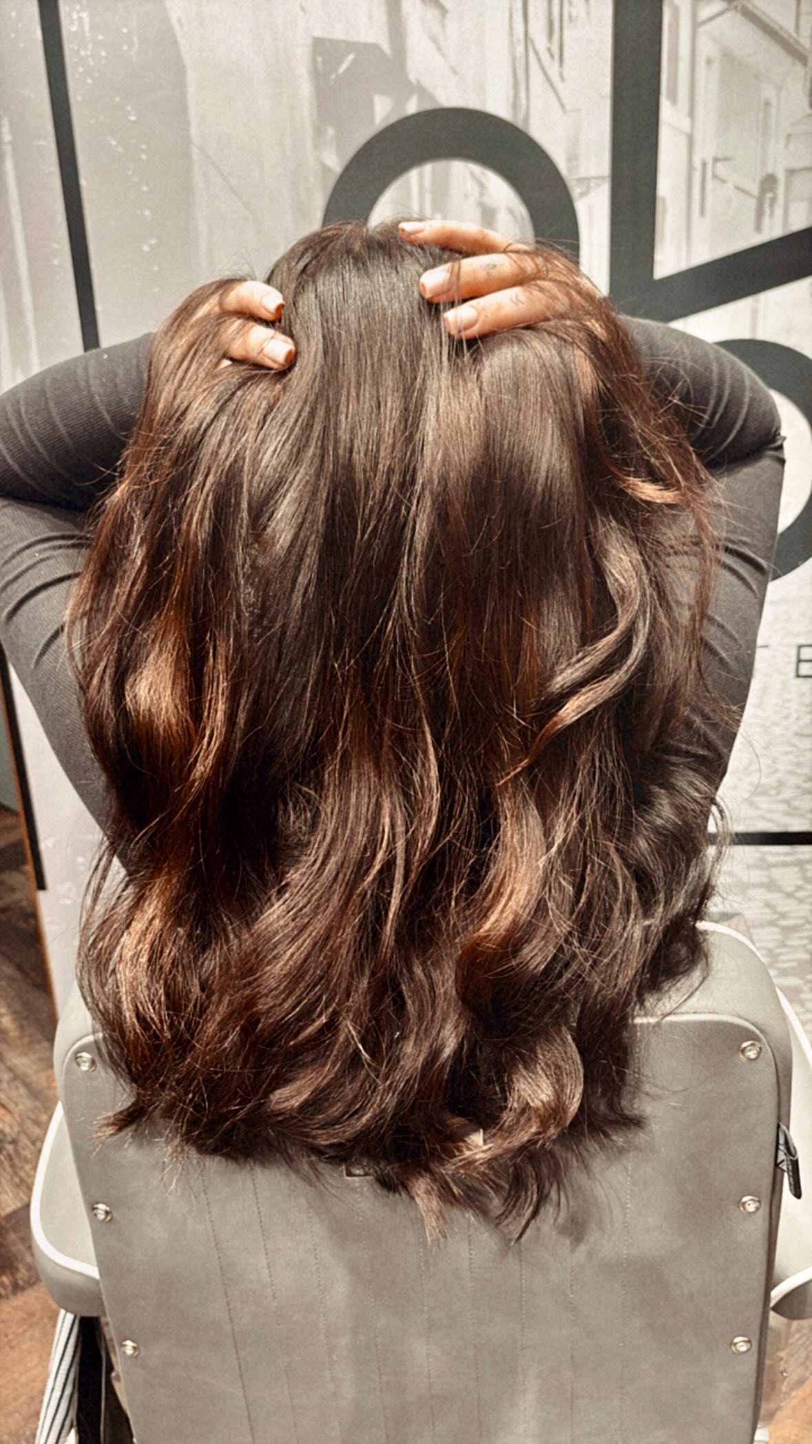 A close-up view of nano-ring hair extensions being fitted to brown hair.